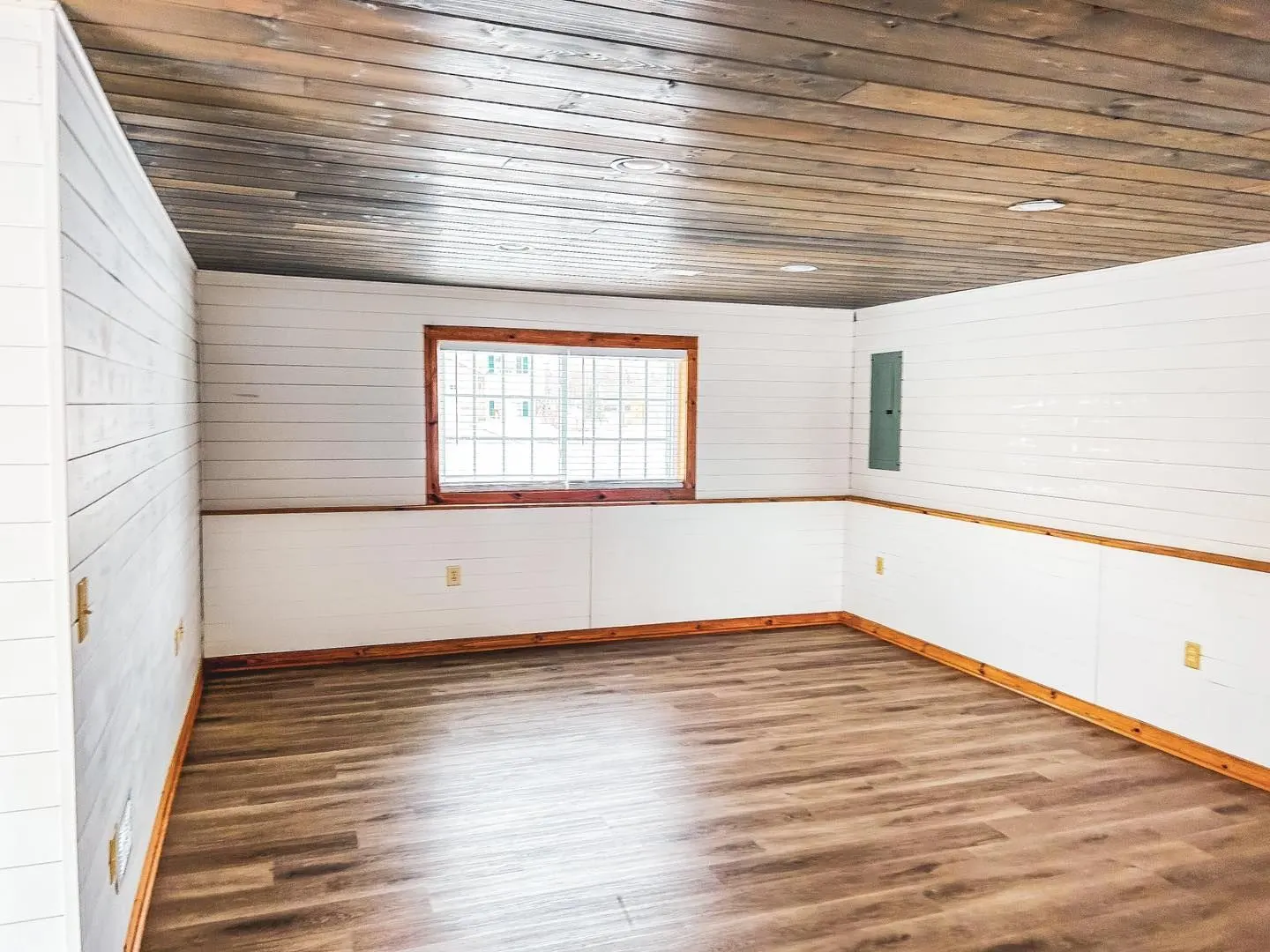 Finished room with white paneled walls, a wood plank ceiling, a window, and a new wood floor